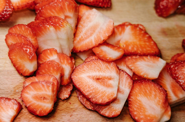 Strawberry cut into pieces, laying on a wooden board
